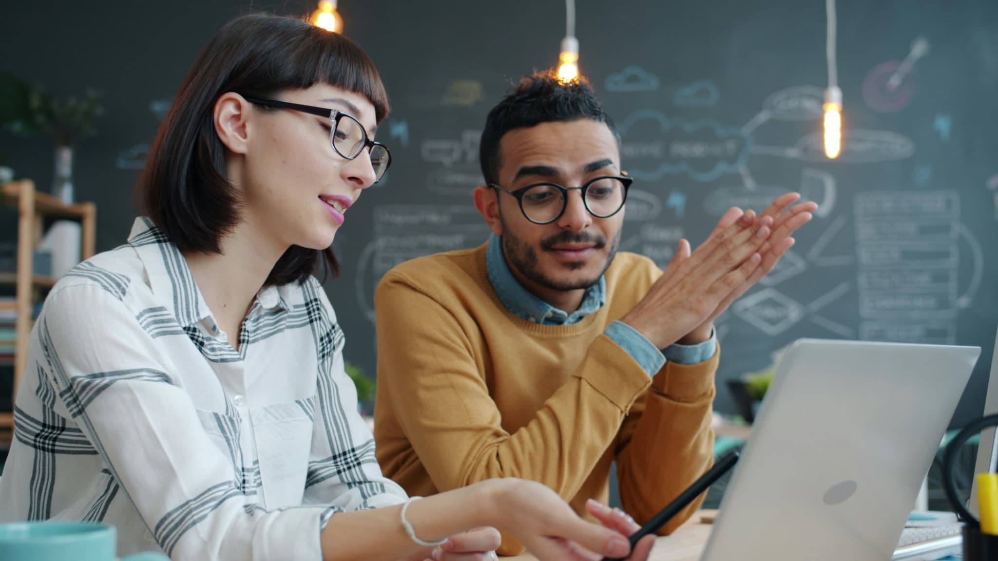 Two colleagues discussing financial information at a laptop