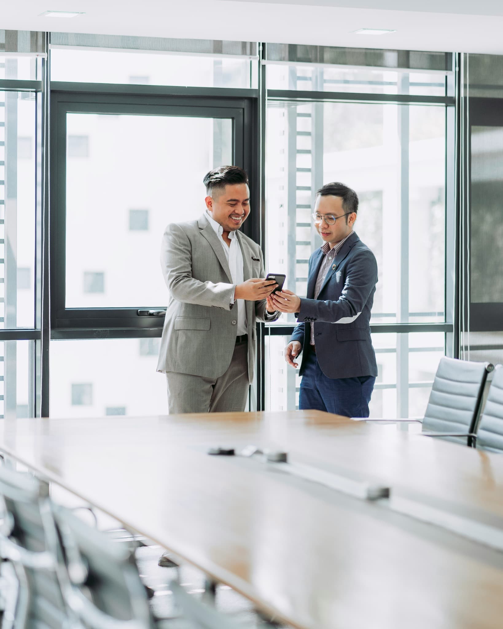 Two professionals looking at a smartphone in a bright meeting room